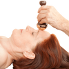 A person massaging a woman's face with Kansa Face and Body Wand