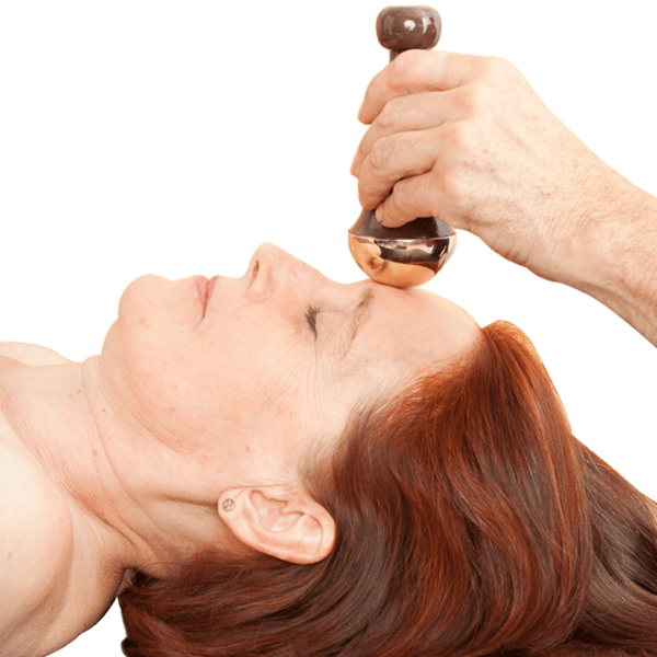 A person massaging a woman's face with Kansa Face and Body Wand